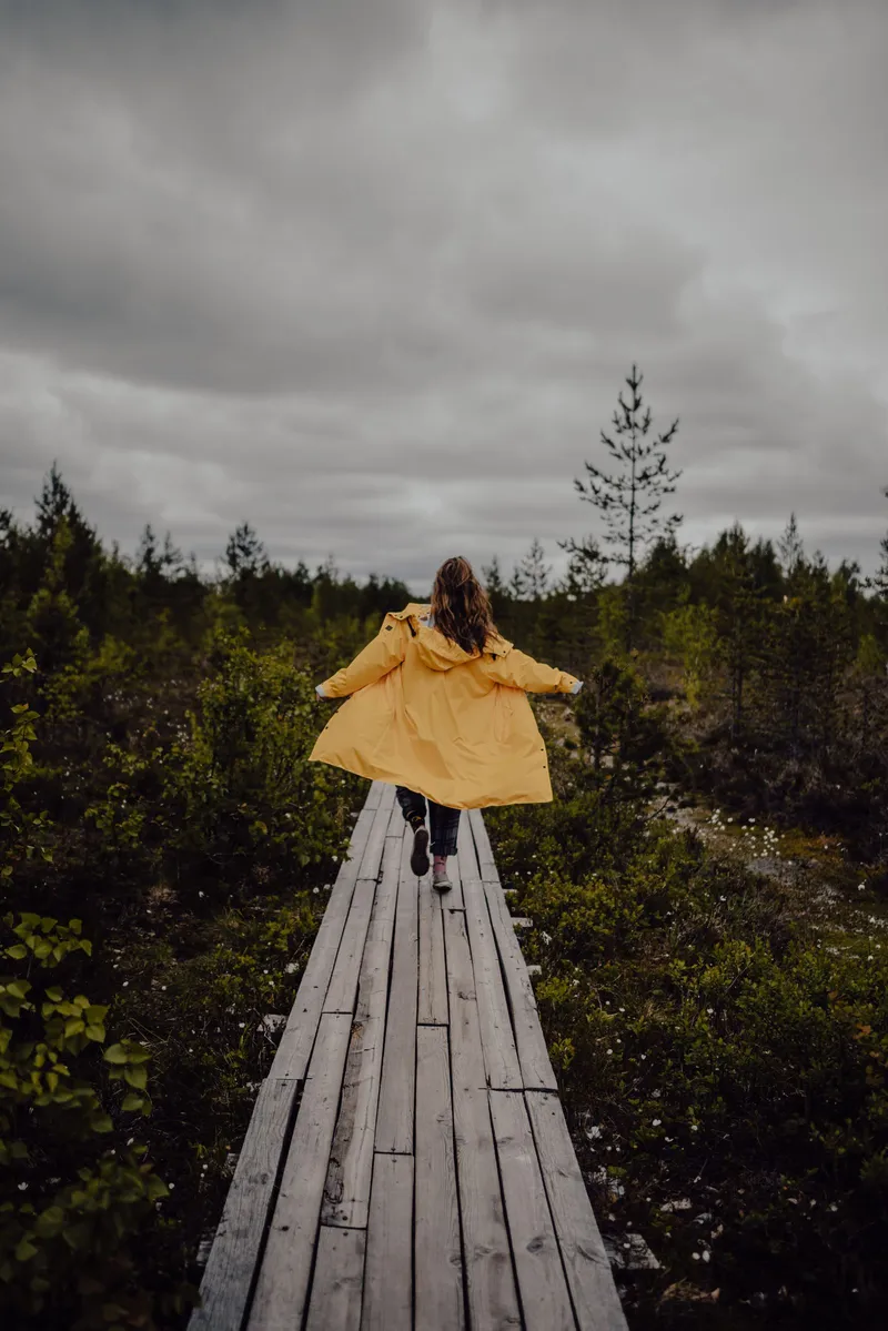 Mujer con chubasquero amarillo corriendo bajo la lluvia