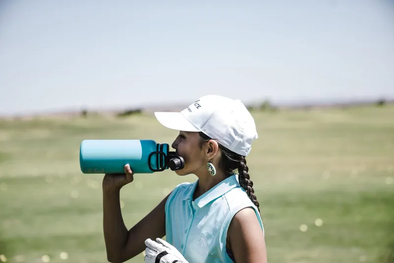 Mujer bebiendo de una botella deportiva al aire libre
